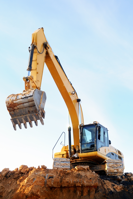 Yellow excavator loader at construction site with raised bucket over blue sky
